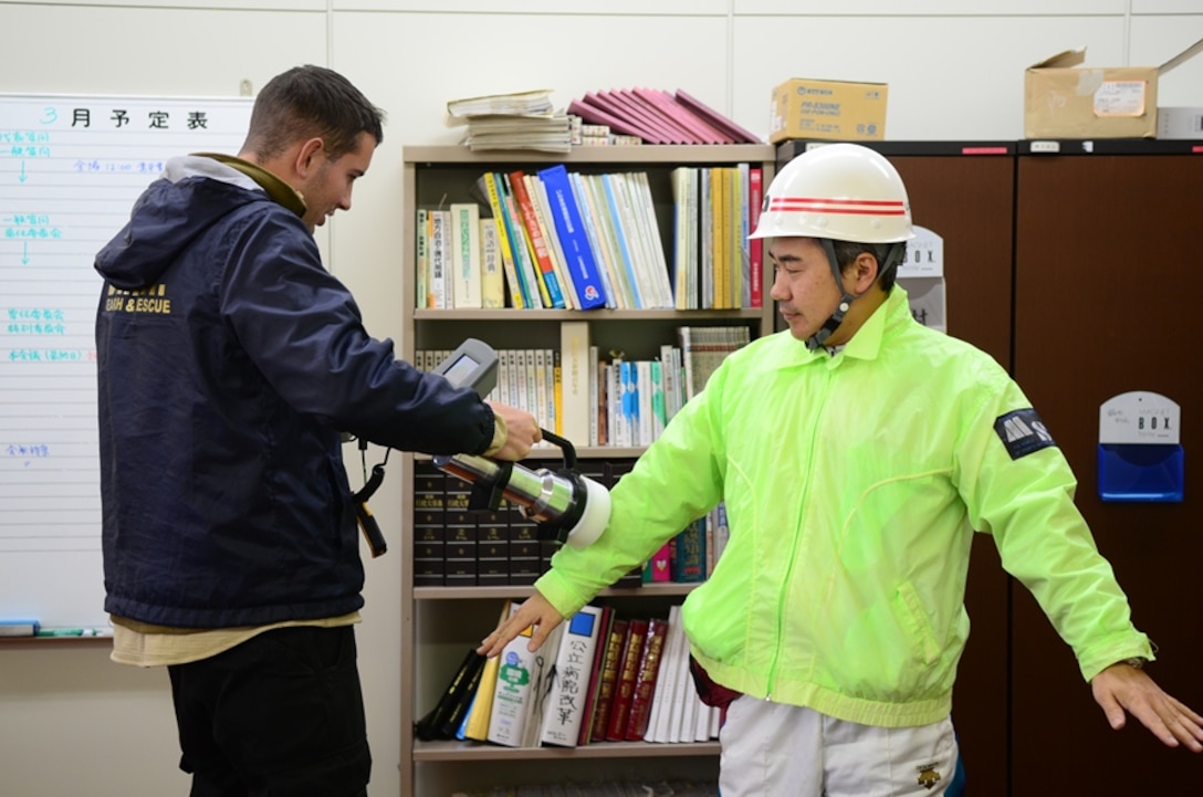 Cpl. Adam Marlatt checks a local council member from Miyagi Prefecture, Japan, for any signs of radioactive contamination in the aftermath of the Fukushima Daiichi nuclear disaster. The councilman had been wearing the same jacket for days as he worked in the disaster zone and was concerned about contamination.